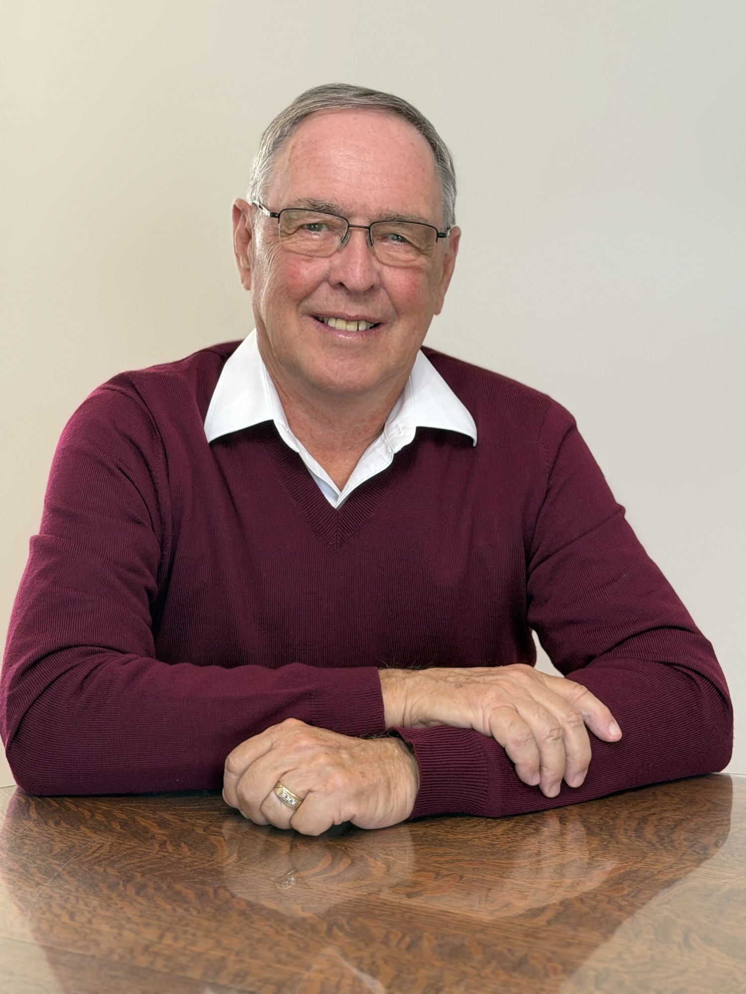 Keith MacCuaig seated at a table in a burgundy sweater