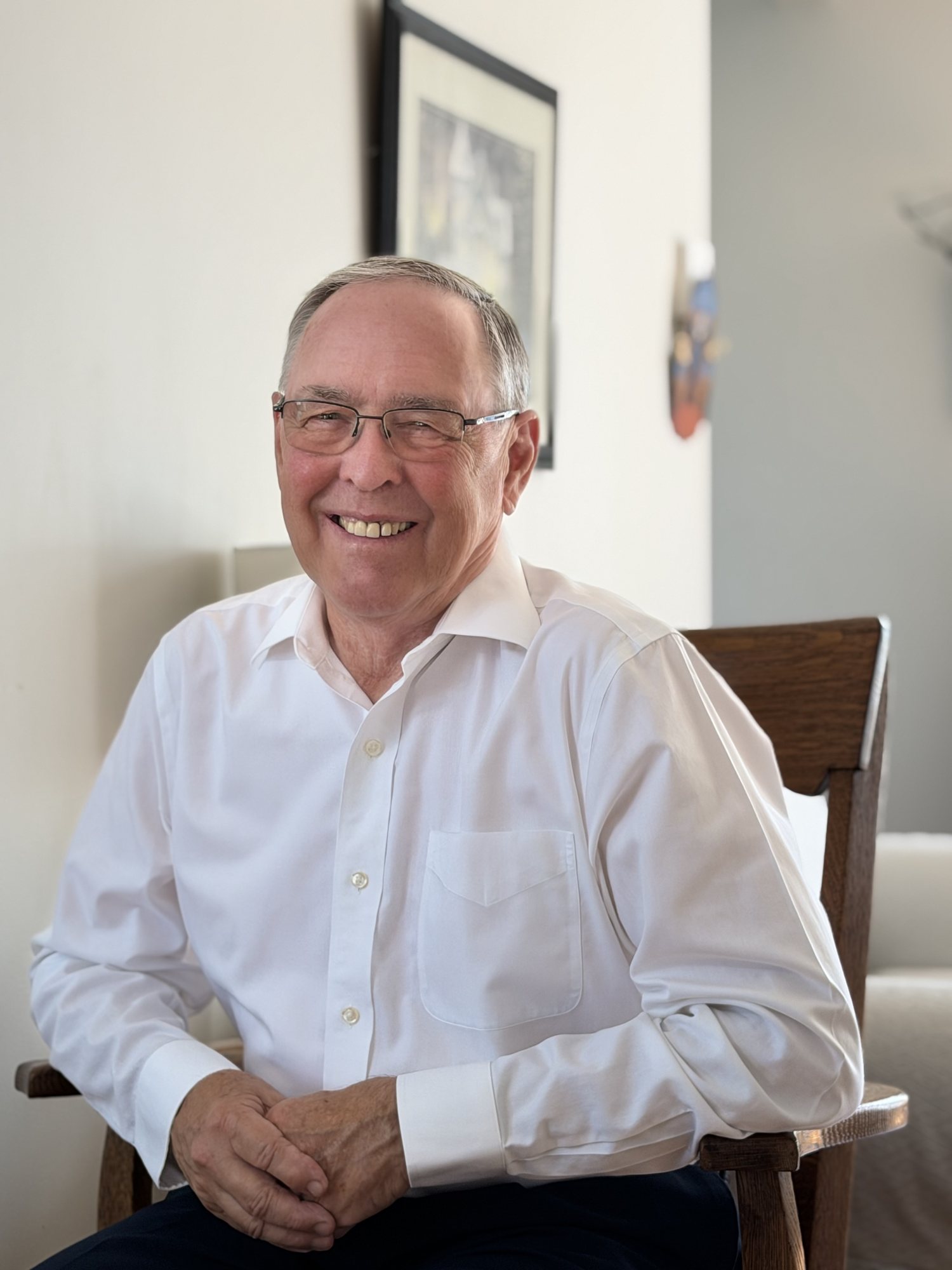 Keith MacCuaig seated and smiling in a white shirt