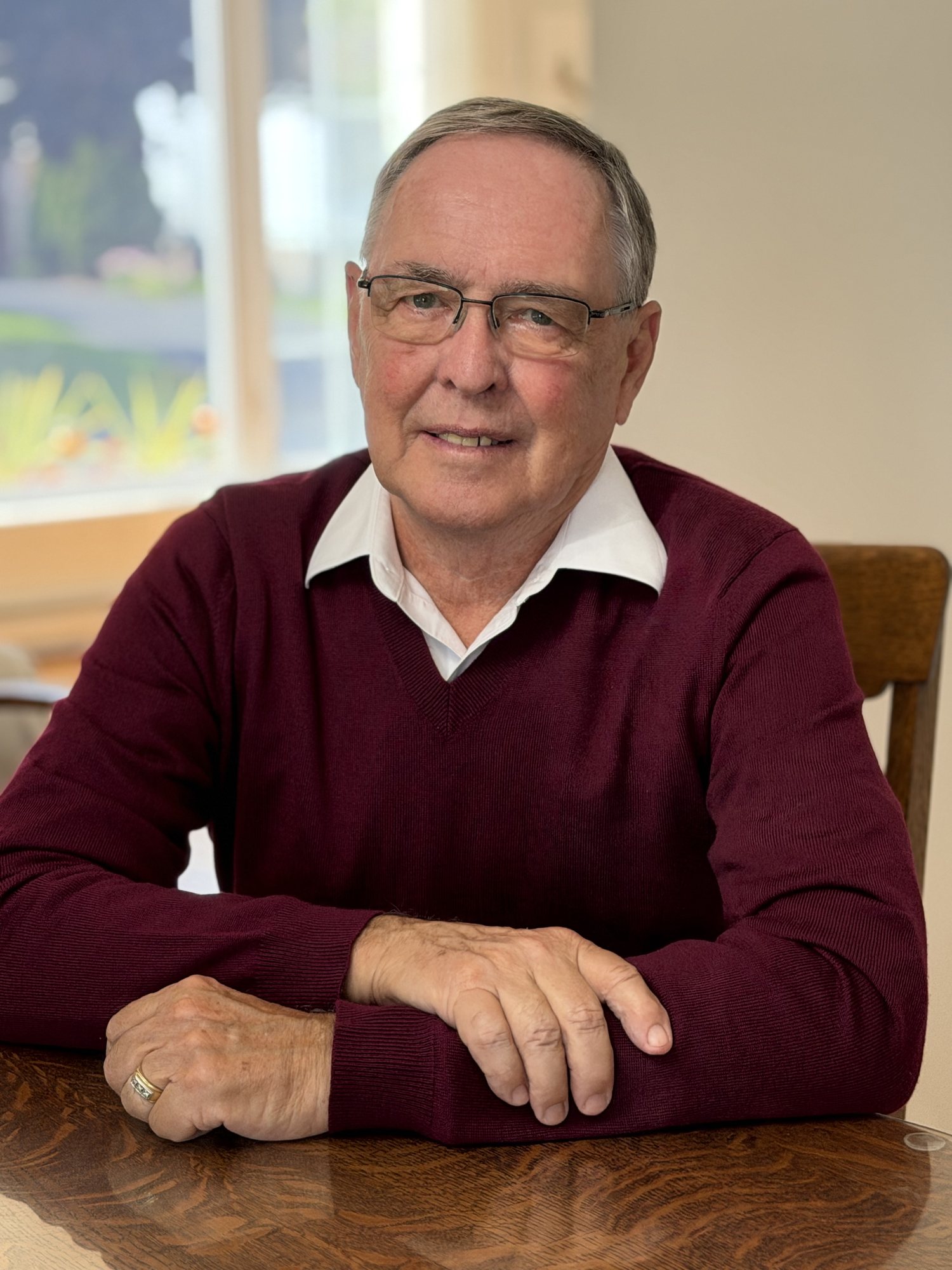 Keith MacCuaig seated at a table in a burgundy sweater